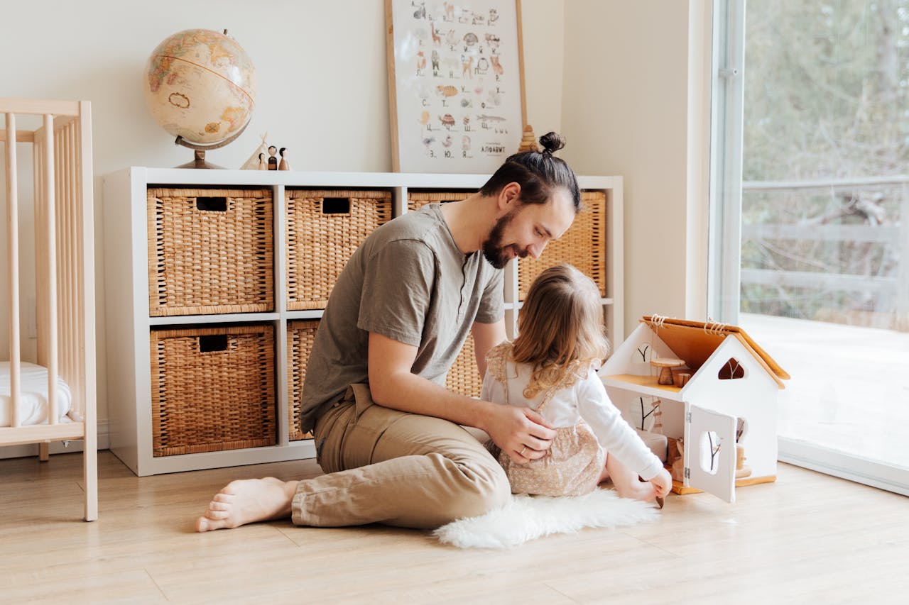gallery-5 Father and young daughter enjoying quality time with a toy house inside a cozy room.